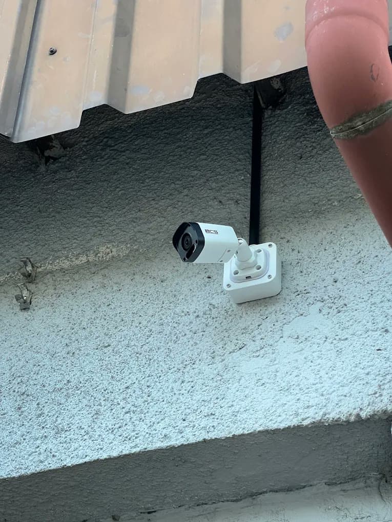 Tubowa kamera IP na puszce przyłączeniowej na elewacji, przewód w osłonie pod okapem